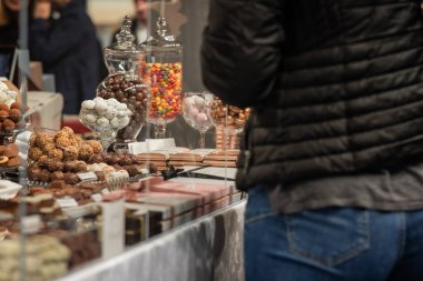 Ekranda farklı tatlılar seçen kişi. Kot pantolonlu, kimliği belirsiz bir kadının sırtında bir sürü çikolata var..