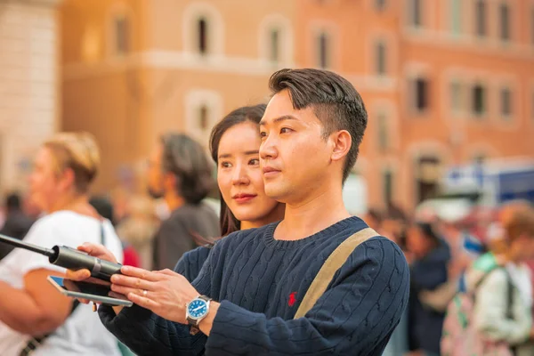 意大利 2023年10月31日 一对亚洲夫妇在罗马市中心的六十三座教堂的纪念碑前 用一根自拍棒做了一个自拍 免版税图库图片