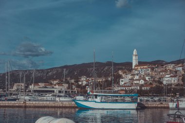 Hırvat Kvarner Sahili 'ndeki Novi Vinodolski' nin panoramik manzarası veya şehir manzarası. Adriyatik Denizi 'ndeki evler güneşli şehir manzarası, ön planda tekneleri olan marina..