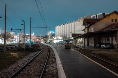 Ljubljana Siska 'nın tarihi tren istasyonunu yenilemek, demiryolunun yanına geçici platformlar yapmak, asfalt koymak ve bir silindirle yuvarlamak. Gece fotoğrafı, uzun pozlama..