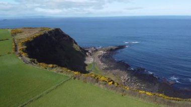 Kuzey İrlanda 'daki Giants geçidinde kayalıklardan, altıgen taşlardan ya da sütunlardan oluşan drone panorama bulutlu bir günde sahilde görkemli bazalt sütunlar. Alanın geniş görünümü..