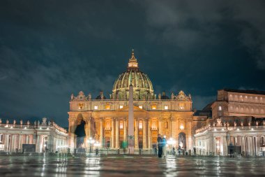 Vatikan 'daki Aziz Peter Meydanı. Arka planda muhteşem bir kilise var. Aziz Peter Bazilikası akşam saatlerinde güzel renkli ışıklandırmalarla.