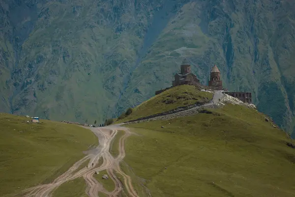 The kazbegi trinity, a magical church and worship place high up in georgian mountains. View from far, majestic background.