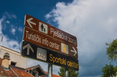 Bosanska Krupa 'da yaya bölgesi, bilgi merkezi ve spor merkezi yönleriyle ilgili bilgi tabloları. İki kahverengi ve bir siyah tahta..
