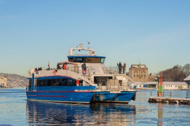 Fiyort gezisi - Bergen 'de bir katamaran gezisi turistleri hızlı bir gezi için fiyortlara götürmek üzere rıhtımdan ayrılıyor. Norveç yolcu gemisi Bergen 'den fiyortlara doğru güneşli bir kış gününde