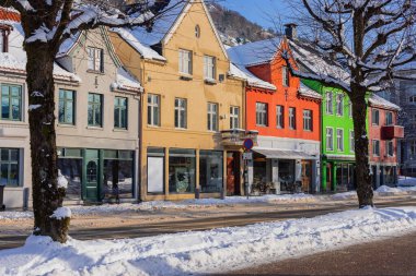Bergen 'de kışın tipik evler, Bergen sokaklarında soğuk kış günü, yollar karla kaplı ve göl kenarındaki uzun renkli evler.