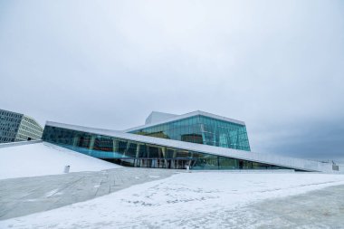 Kış ortasında Oslo 'daki Opera binasının destansı manzarası. Opera binasının üstündeki bulutlu hava, karla kaplı ve sarılı. Modern mimari