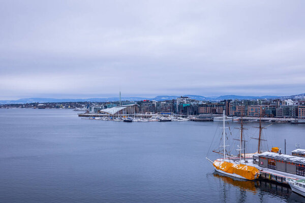 View from askerhus fortress towards the Aker Brygge part of the city, with fancy boats moored and fantastic architecture behind. Cloudy winter day.