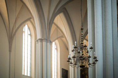 Yüksek çatısı ve beton sütunları olan gotik bir kilisede modern ampulleri olan bir avize. Süslü güzel bir kilise..