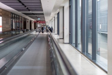 Berlin Schonefeld Havaalanı 'nda iç geçit, görünür yürüyüş yolları ve uzun sokaklar. Bazı insanlar çıkışa doğru yürüyorlar. Havaalanı aktarımı