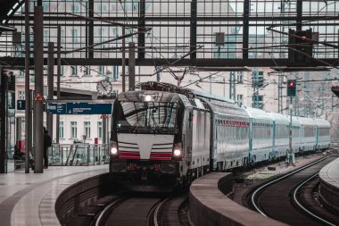 Yolcu treni serin bir bahar gününde Berlin Friedrichstrasse istasyonuna yaklaşıyor. Solda, görkemli tren istasyonu yapısında insan olmayan tipik bir platform görülüyor..