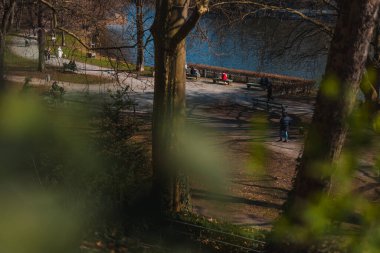 İnsanlar Berlin 'in Charlottenburg banliyösündeki Lietzensee parkında dinleniyor ve yürüyüş yapıyorlar. Parkta güzel bir bahar günü