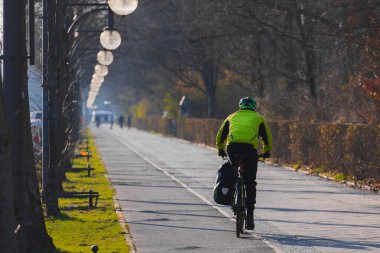 Berlin 'de banliyö bisikletçisi. Berlin 'in göbeğinde bisiklet süren bir insanın arka plan manzarası, güzel bahçeler ve sokak lambaları.