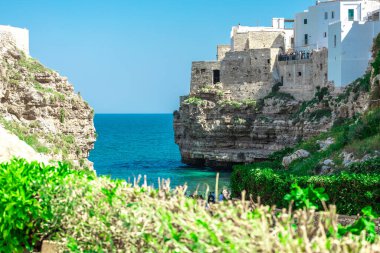 Polignano a Mare, şehir kayalıkları arasında plajı olan güzel bir şehir. Güneşli bir bahar gününde İtalya 'da pitoresk bir köyün renkli bir resmi.