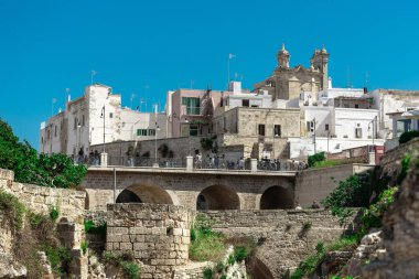Polignano a Mare 'de kemer köprüsü, şehir kayalıkları arasında plajı olan güzel bir şehir. Güneşli bir bahar gününde İtalya 'da pitoresk bir köyün renkli bir resmi.