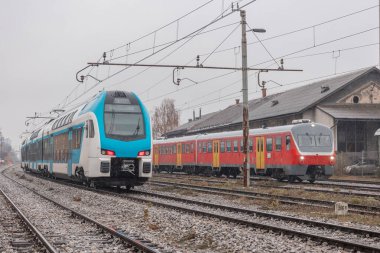 Bitişikteki tren raylarında eski ve yeni yolcu trenleri. Demiryolu taşımacılığında yenilere yol açmak için eski yöntem.