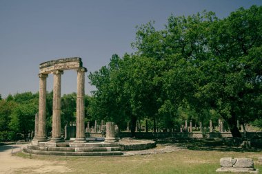 Yunanistan 'ın Olympia antik sahasında güneşli bir günde alınan farklı sütunlar veya sütunlardan oluşan arkeolojik harabelerin manzarası