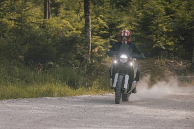 Çakıl taşı yüzeyinde modern macera motosikleti. Doğada ya da off-road 'da motosiklet sürmek, özgürlüğün tadını çıkarmak. Ormanda motosiklet. Dönüyorum.