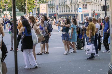 PARIS, FRANCE, 23.7.2024: Zamandan keyif alan rastgele insanlar ve Paris 'teki ünlü Moulin Rouge şehir simgesi etrafında fotoğraf çekiyorlar. Manzara çeken kadınlar