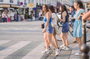 PARIS, FRANCE, 23.7.2024: Bir grup genç kadın Paris 'te Moulin Rouge Cazibesi önünde karşıdan karşıya geçiyor.