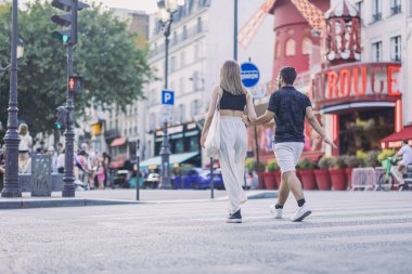 Paris 'teki ünlü Moulin Rouge' un önünden geçen kimliği belirsiz bir çiftin arka görüntüsü. Çiftler şehir turu yapıyor.