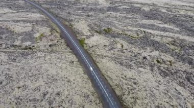 Bulutlu bir yaz gününde Snaefellsnesvegur, Islandija yakınlarındaki Lav kayaları boyunca uzanan hava yolu. Muhteşem lav tarlaları ve delici yollar. Araba yolda gidiyor.