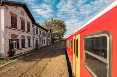Istrian tren hattındaki Podgorje 'nin resim tren istasyonu. Görkemli taş bina kırmızı bir yolcu treninden görünüyor.