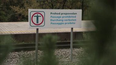 İstasyondaki tren raylarını yasaklamak için levha, Sloven, İngilizce, Almanca ve İtalyanca gibi birçok dilde yazılmış.