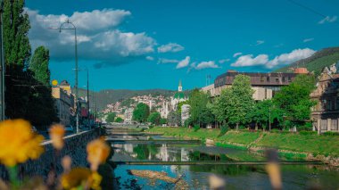Miljacka Nehri, çağdaş müzeye yakın görünen çağlayanlar ve köprülerle yavaşça Saraybosna 'dan geçiyor. Mavi gökyüzü ve yeşil tepeler