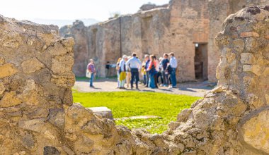 Pompei arkeoloji sahasında rehber dinleyen bir grup turist. Bulanık turistlerin harabelerdeki duvardaki delikten baktığı manzara. İyi bir turist arkaplan fotoğrafı