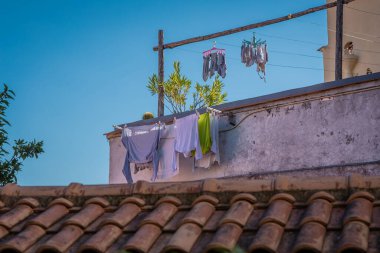 Napoli, İtalya 'da bir binanın tepesindeki balkonda giysileri kurutmak. İtalya 'nın Napoli şehrinde çatıların üstündeki giysilerin tipik kurutulması, sıcak sonbahar güneşinin kurumasını sağlar.