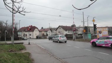 LJUBLJANA, SLOVENIA, 15.4.2024: Uyarı ışıkları açıkken ve engeller indirilirken demiryolu üzerinden geçen arabalar. Trenle şans oyunu oynayan tehlikeli sürücüler. Çılgın bisikletçiler ve yayalar..