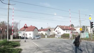 LJUBLJANA, SLOVENIA, 15.4.2024: Uyarı ışıkları açıkken ve engeller indirilirken demiryolu üzerinden geçen arabalar. Trenle şans oyunu oynayan tehlikeli sürücüler. Çılgın bisikletçiler ve yayalar..