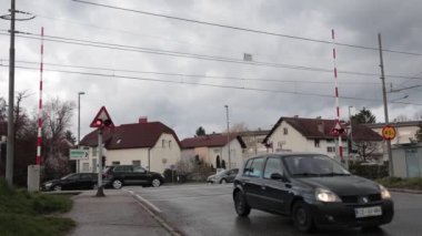 LJUBLJANA, SLOVENIA, 15.4.2024: Uyarı ışıkları açıkken ve engeller indirilirken demiryolu üzerinden geçen arabalar. Trenle şans oyunu oynayan tehlikeli sürücüler. Çılgın bisikletçiler ve yayalar..