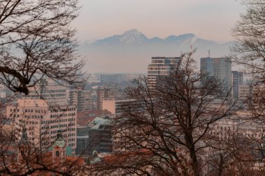 Ijubljana Kalesi 'nden muhteşem bir kış akşamı arkaplanı. Önünde oteller ve gökdelenler olan görünen güzel Kamnik dağları.