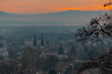 Trnovo 'nun akşam panoraması, Ljubljana' nın banliyösü, görünür ünlü kilise ve rezidans blokları. Güneş sadece kış sisinde batıyor.