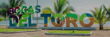 Bocas del Toro tabelası, önünde fotoğraf çekmek için sahilde büyük harfler. Turistik yerleri gösteren tipik işaretler