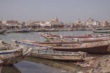 Fishing boats parked on the shore in Sant Louis, a city in northern Senegal. Colorful boats, called pirogues are waiting in a canal of sengal river with dirty water clipart