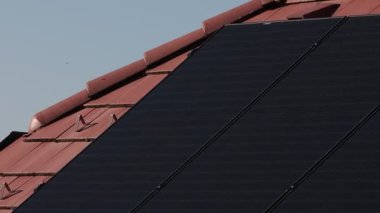 Evdeki evin kırmızı kiremit duvarına elektrik için çoklu güneş panelleri yerleştirildi. Modern güneş enerjisi, çevre dostu enerji üretimi, güneşli bir gün..