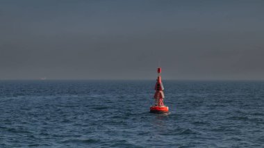 Okyanusta yüzen kırmızı şamandıra kıyıya yakın. Gemiler ve diğer gemiler için denizde yol gösteren bir fener..