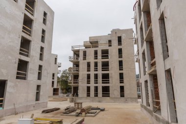 Şehir blokları yapım halinde. Beton ve kırmızı tuğlalardan yapılmış modern konutların tipik inşaat alanı. Birden fazla ev görünüyor..