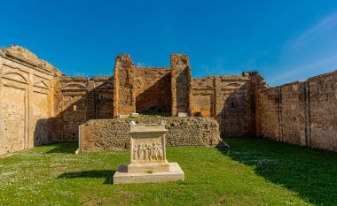 Pompei arkeolojik alanındaki harabelerin genel görünümü, görünür sütunlar ve çimen verandalı duvarlar veya evin merkezi kısmı görünür.