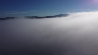 Hava aracı, planinsko polyesinin üzerindeki bulutları sabah erken saatlerde ortaya çıkardı. İnsansız hava aracı sisli bir seviyeden sabah bulutların üstüne yükselir..