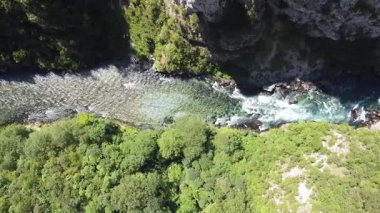 Piva Nehri Kanyonu 'nun Vadi üzerindeki yüksek yol köprüsünün yakınındaki Piva Nehri geçidine dikey drone görüntüsü. Arka planda yeşil dikey kaya oluşumları ve mavi gökyüzü, Mratinje hidroelektrik barajını kapatın