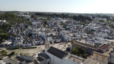 Alberobello köyünde dar sokakları olan güzel Trulli evlerinin insansız hava aracı görüntüsü. İtalya 'nın güneyindeki Apulia' da bir tepede resim gibi bir köy. Akşam ayarı, pürüzsüz drone hareketleri.