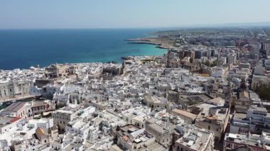 Güneşli bir bahar gününde İtalya 'nın Puglia bölgesindeki Monopoli şehrinin geniş insansız hava aracı panoraması. Görünür liman ve eski evler. Drone tavası sola.
