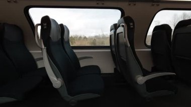 Banliyö koltukları olan modern çift katlı bir trende koltukların ve pencerelerin yan görüntüsü. Tren kırsalda koşuyor, güzel tren yolculuğu..