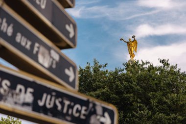 View of fontaine de palmier in paris with visible statue of victory sticking out from the trees. Direction signs in the foreground. clipart