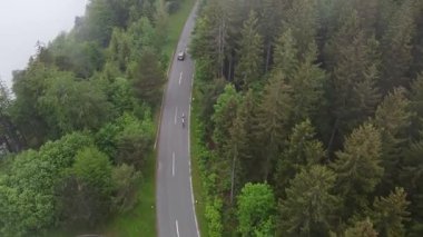 Kötü adam Alpenpanorama yolundaki dobratsch 'a doğru giden yol bisikletçilerinin hava aracı görüntüsü. Dağda bulutlu yağmurlu hava, yeşil ağaçlar.