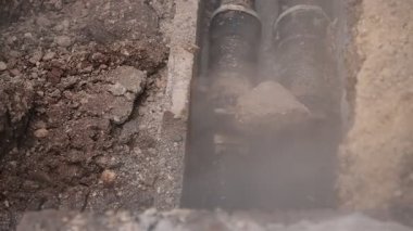 Sızdıran buhar ısıtma hattı ya da ısıtma boru hattı. Yerdeki delikten yükselen buhar görüldü, yerde su yoğunlaşıyor..